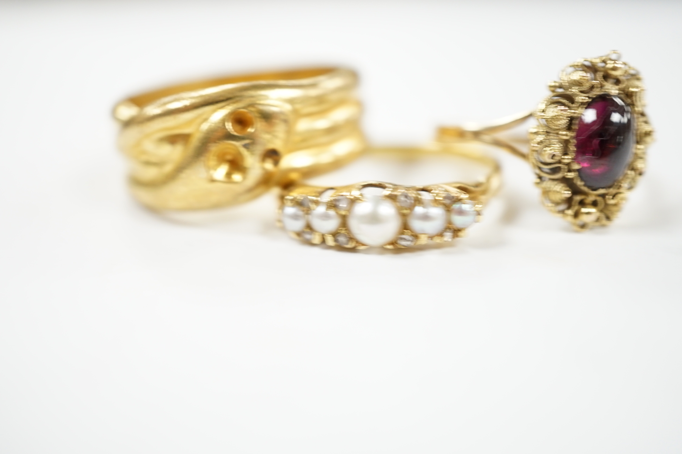 A yellow metal and cabochon garnet set ring, an Edwardian 18ct and graduated split pearl set half hoop ring, with diamond chip spacers and one other ring.